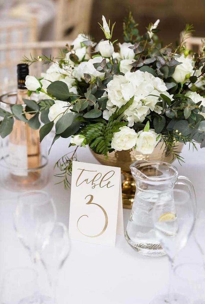 A table with a vase of flowers and a table number