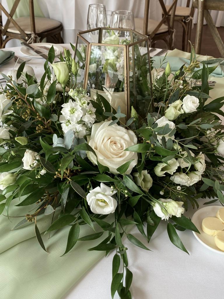 A table is decorated with white flowers and greenery