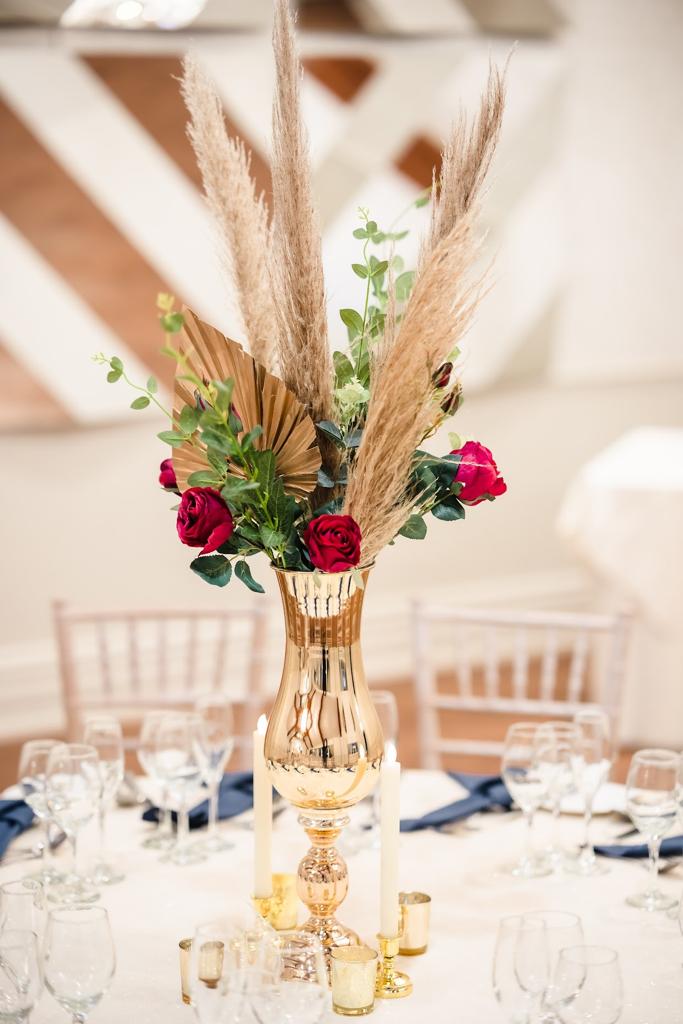 A gold vase filled with flowers and candles on a table