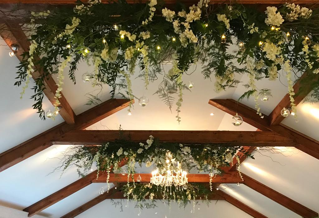 A chandelier hangs from the ceiling with flowers hanging from it