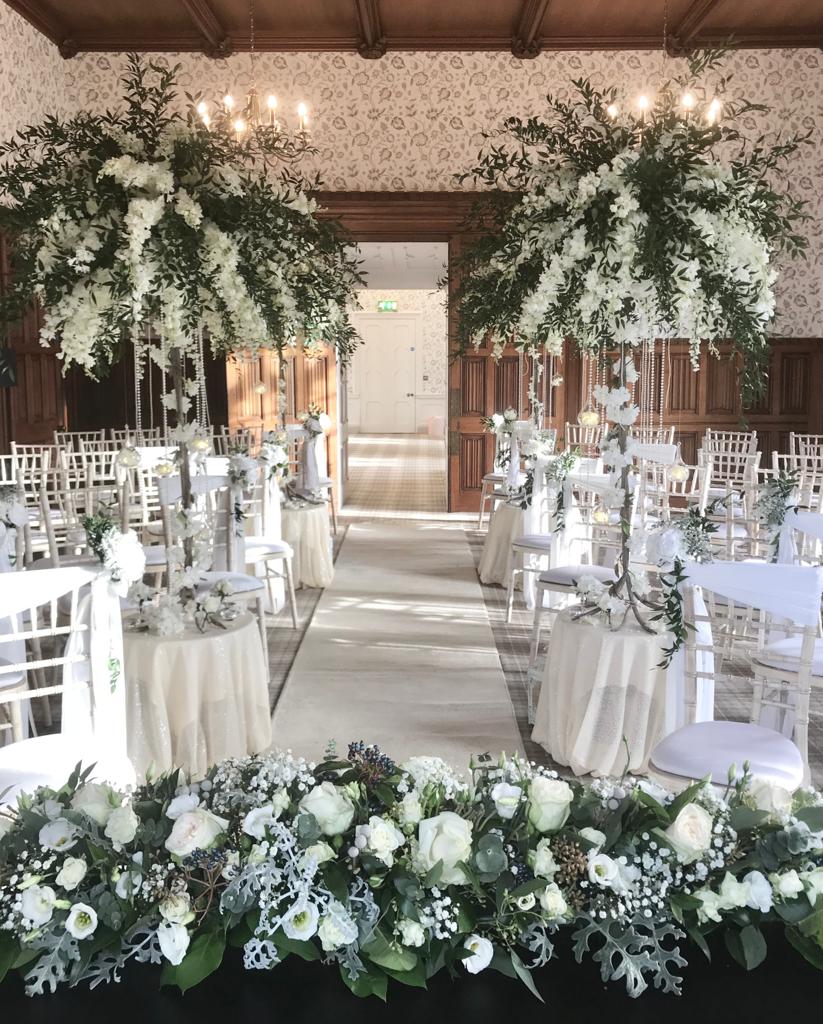 A room with tables and chairs decorated with white flowers and greenery