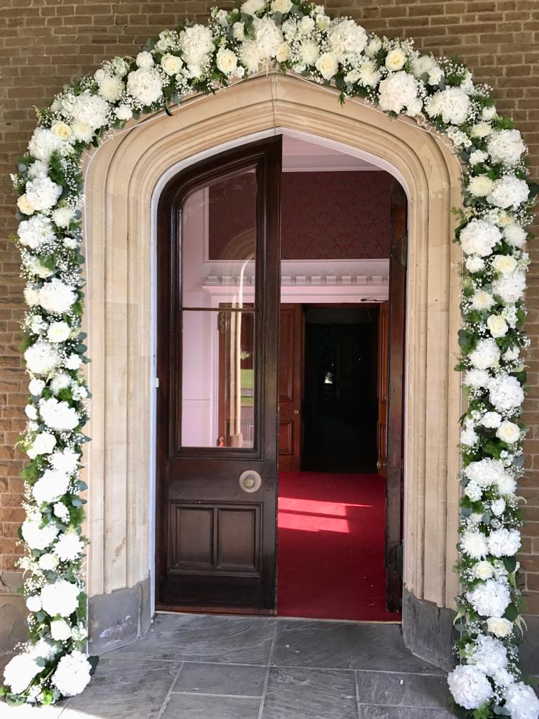 A door is decorated with white flowers and greenery