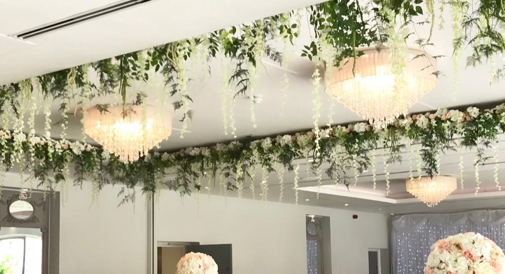 A room with flowers hanging from the ceiling and chandeliers