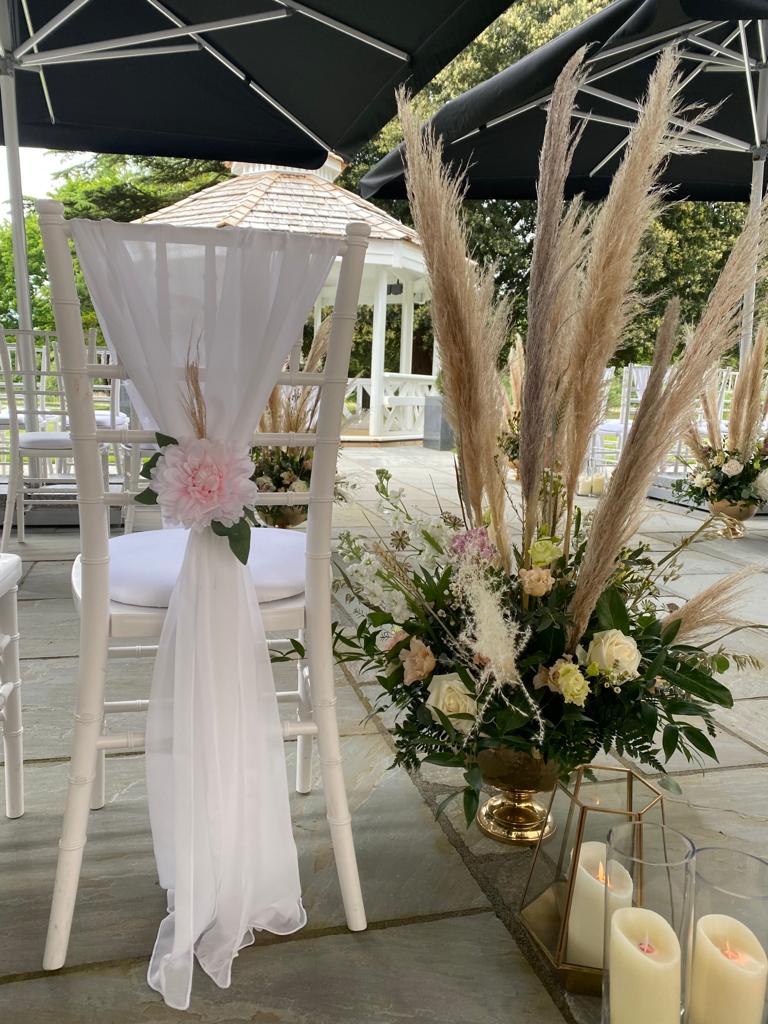 White chairs with flowers and candles in front of them