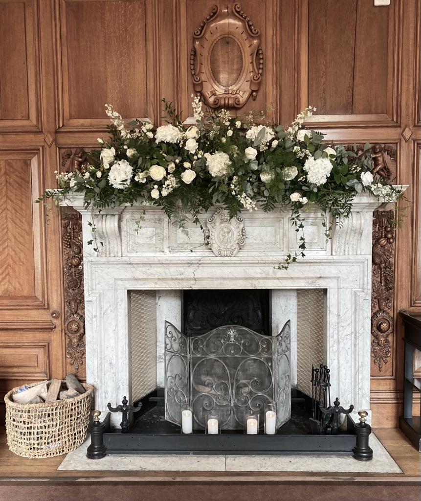 A fireplace with candles and flowers on it