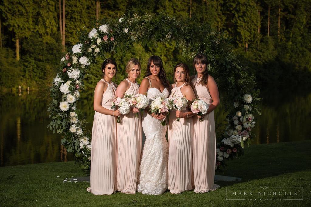 A bride and her bridesmaids are posing for a photo by mark nicholls photography