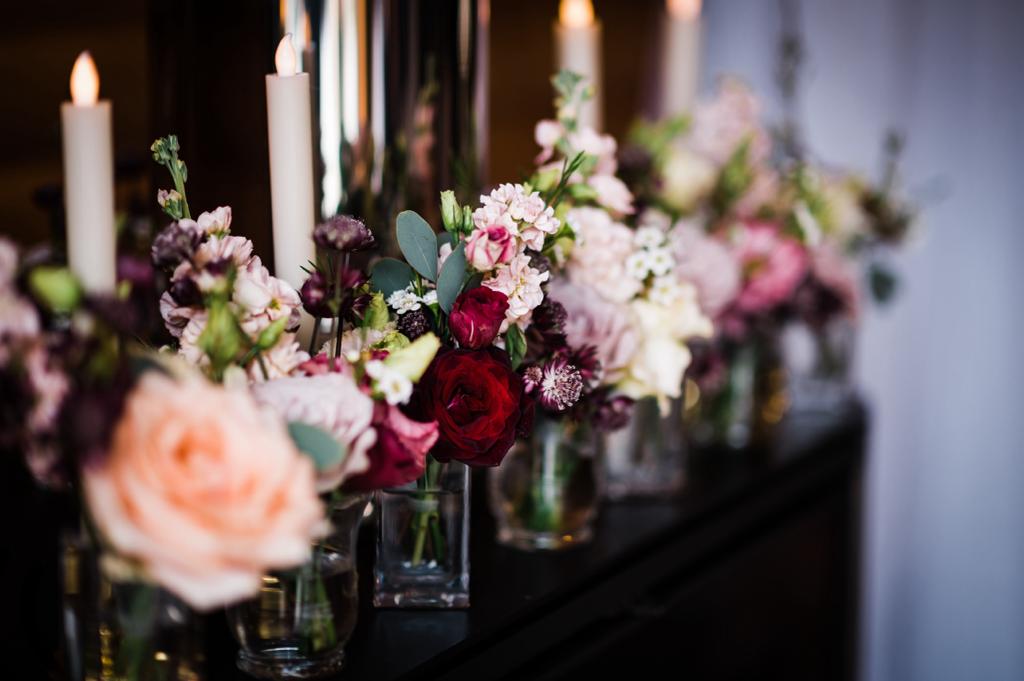 A row of vases with flowers and candles on a table