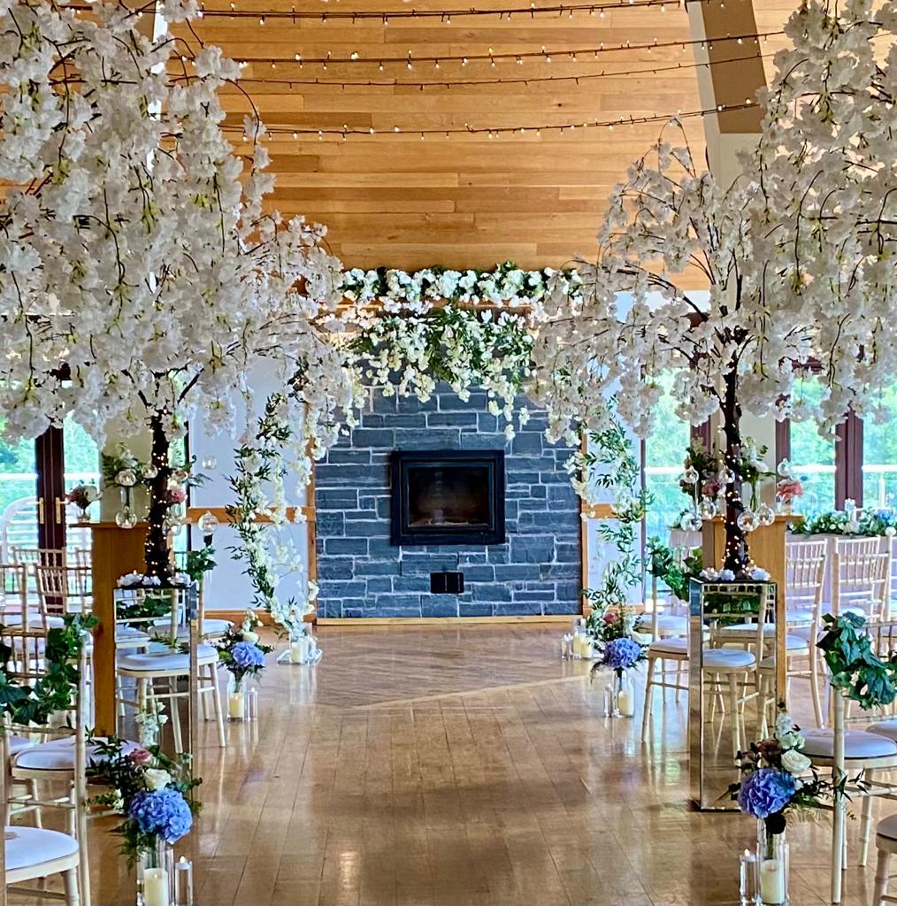A row of chairs are lined up in front of a fireplace decorated with white flowers