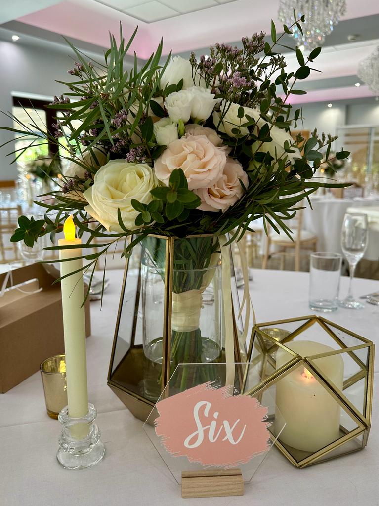A table with a vase of flowers and a six sign on it