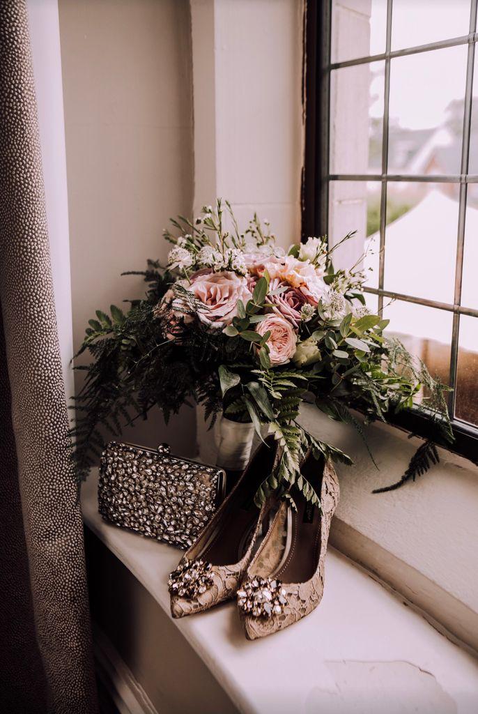 A bouquet of flowers and a pair of shoes on a window sill
