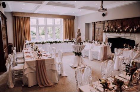 A room filled with tables and chairs and a wedding cake on a table .