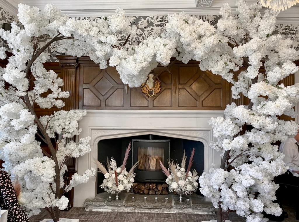A fireplace surrounded by white flowers and trees