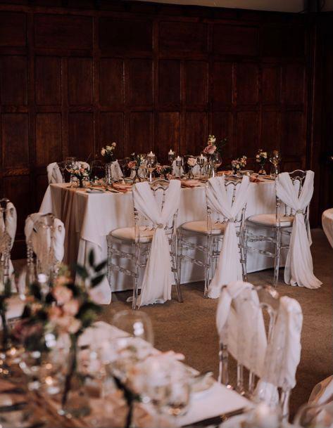 The chairs are decorated with white ribbons and flowers for a wedding reception .