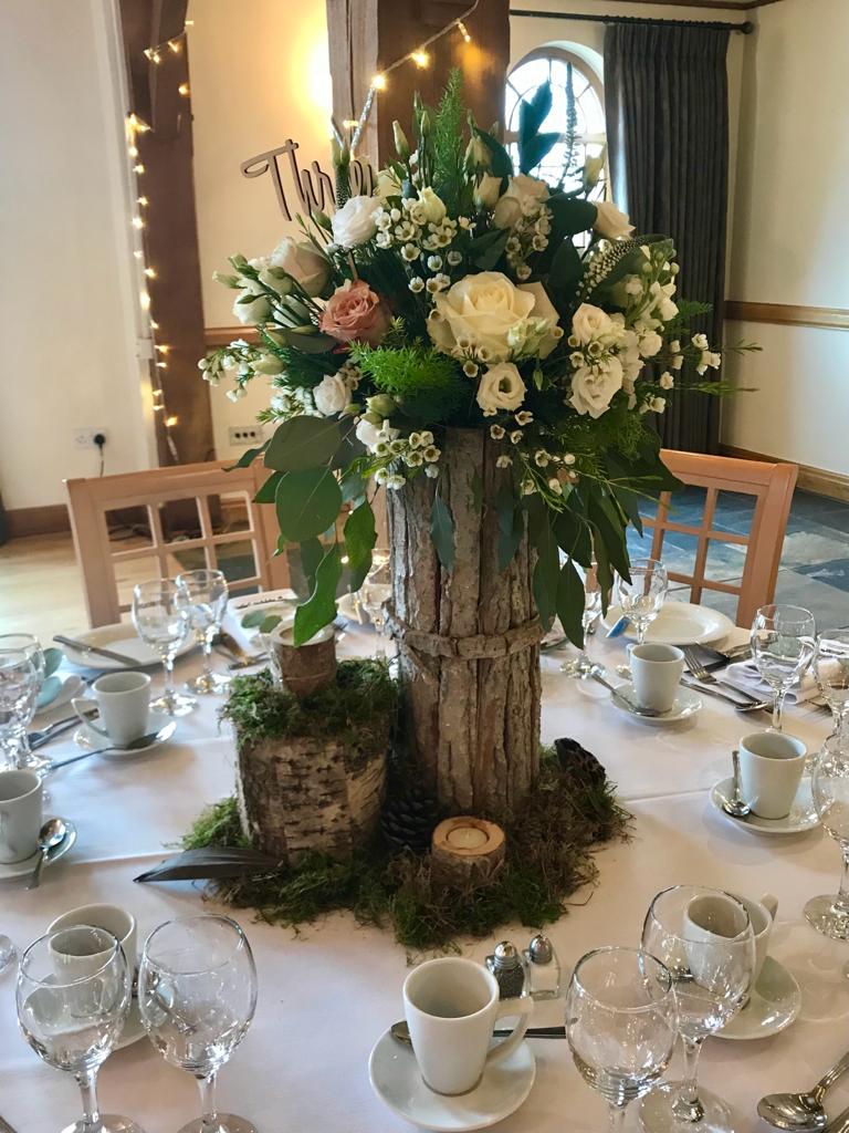 A table set for a wedding reception with a wooden trunk filled with flowers