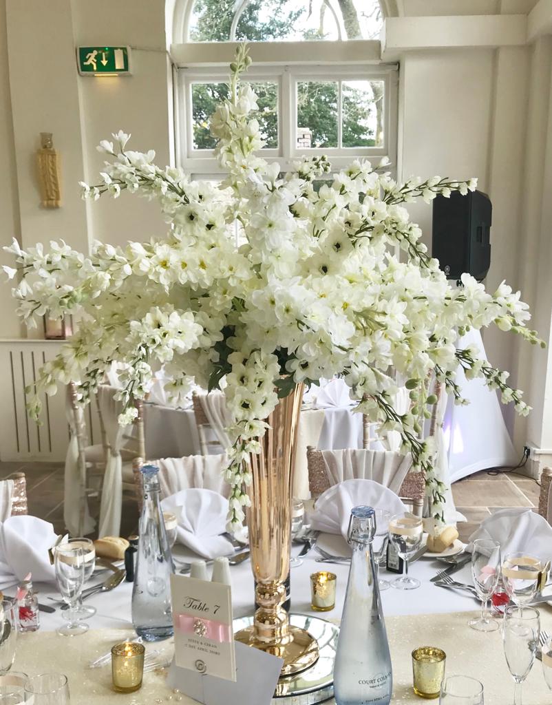 A table with a vase of white flowers and a table number 7