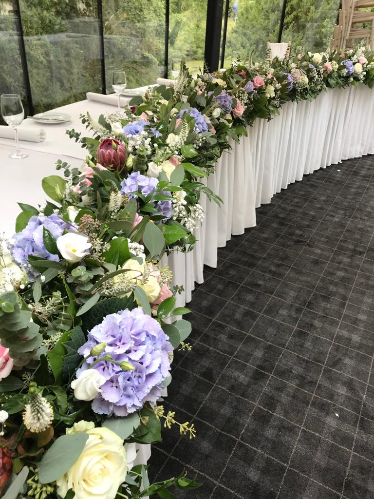 A long table with flowers on it and a white table cloth