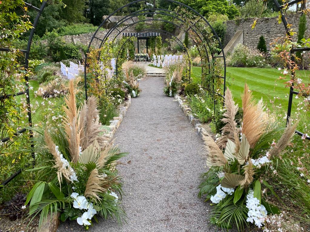 A path lined with flowers and plants leading to a gazebo