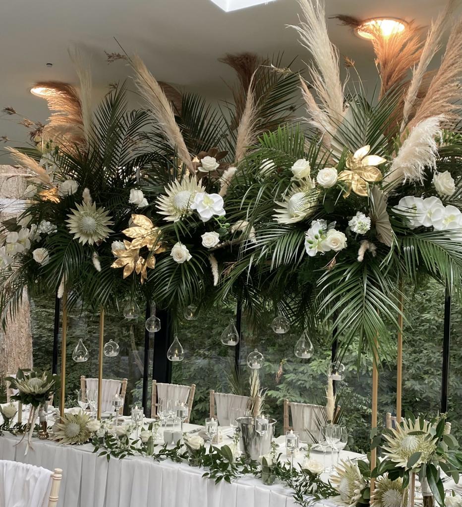 A long table is decorated with white flowers and greenery