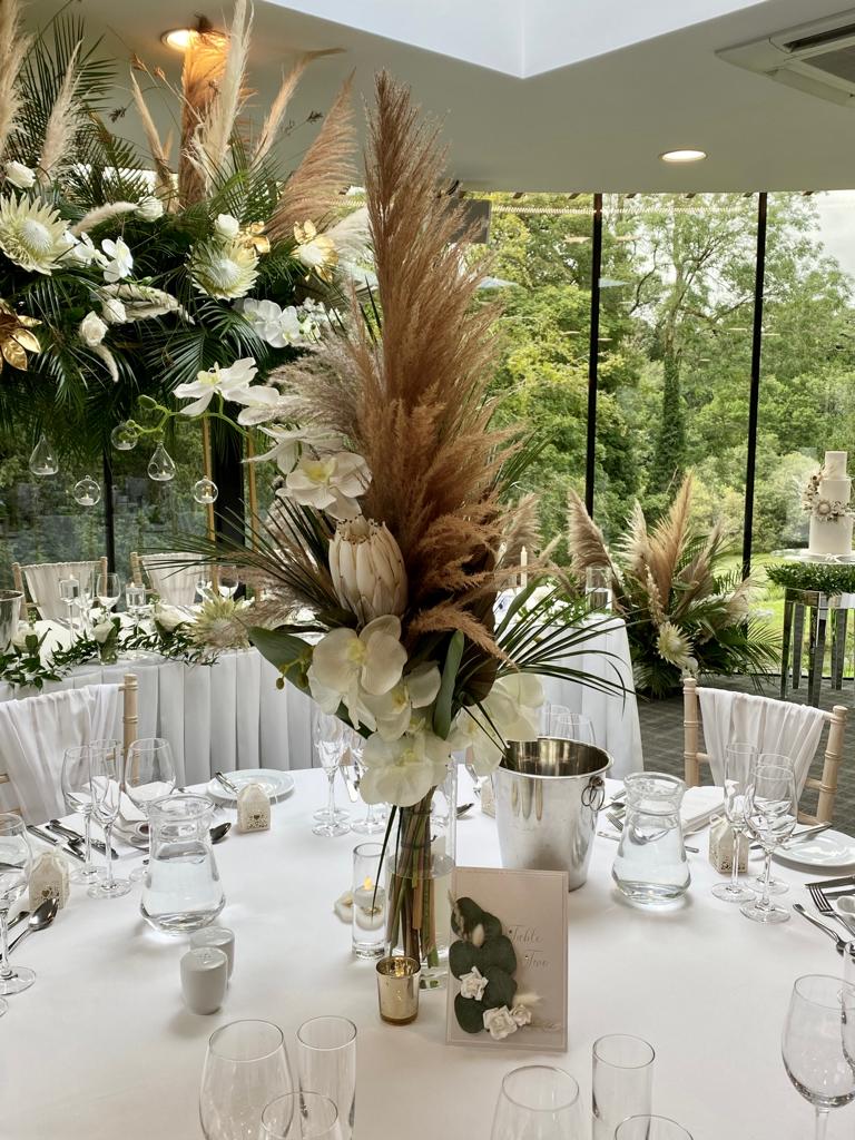 A table set for a wedding reception with a vase filled with flowers