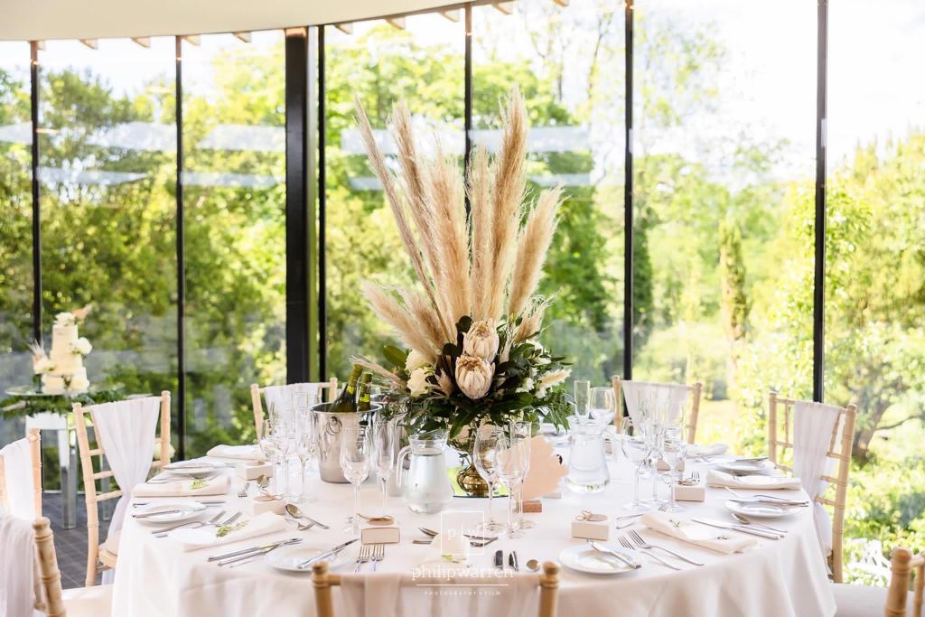 A table set for a wedding reception with a vase of flowers on it
