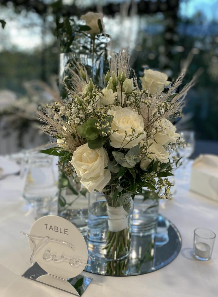 A table with a vase of white flowers and a table number