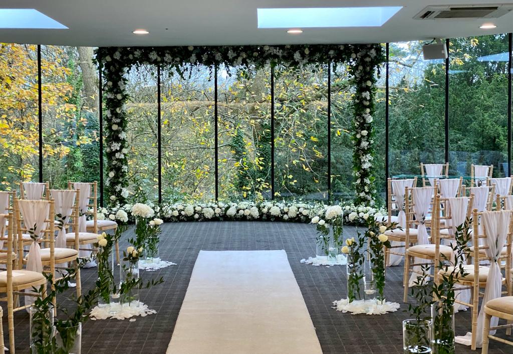 A wedding ceremony is set up in a room with lots of windows