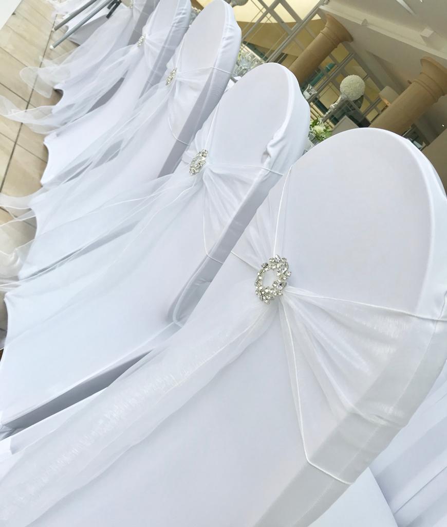 A row of white chairs with rhinestones on the backs