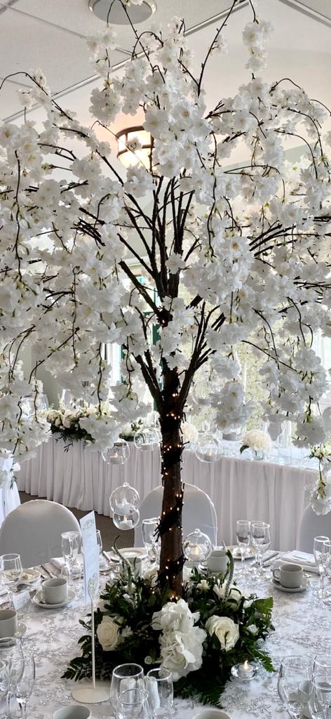 A tree with white flowers on it is on a table