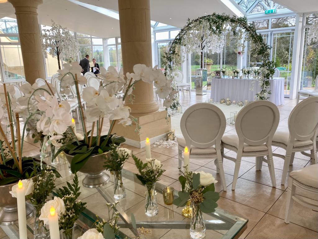 A room with white chairs and flowers and candles on a table