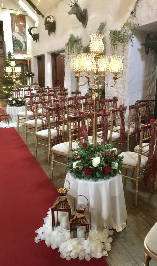 A table with candles and flowers on it in front of a row of chairs