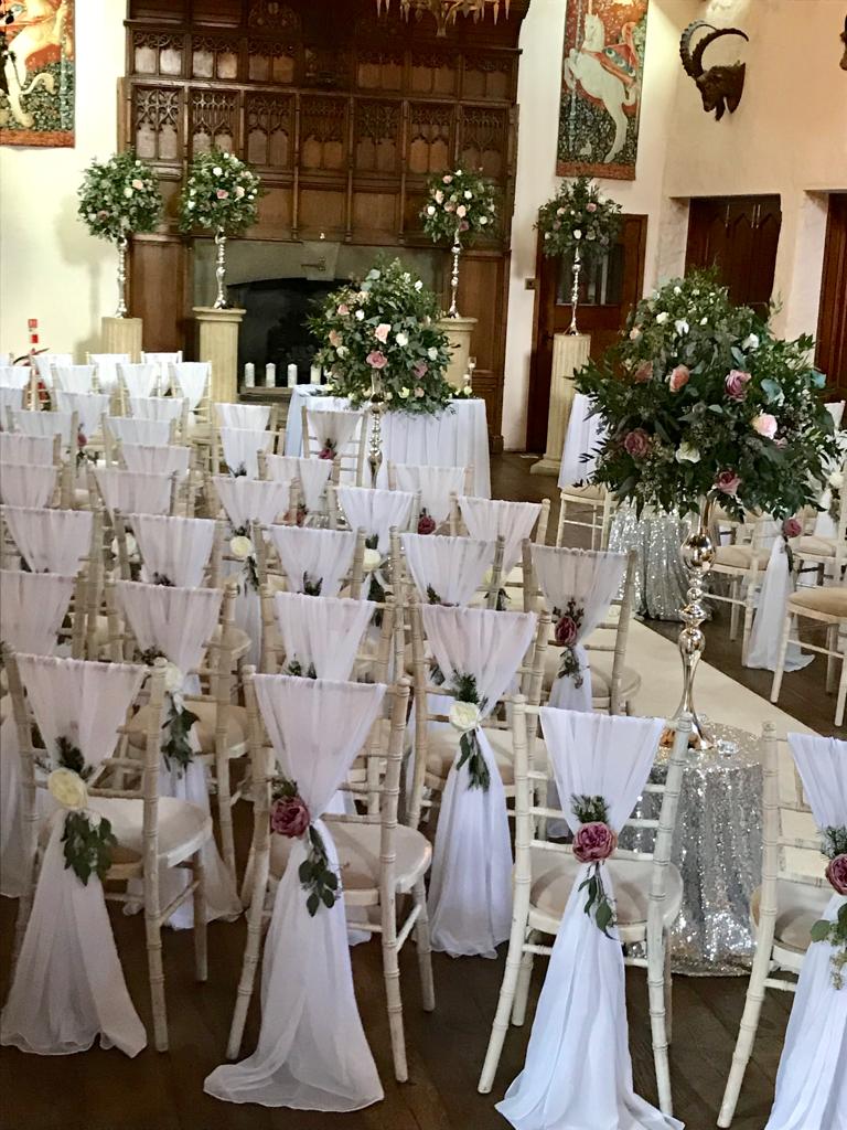 A row of white chairs with flowers on them