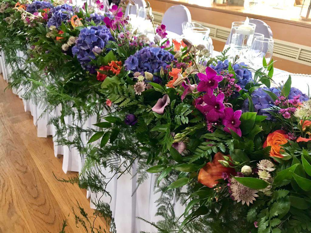 A long white table with a bunch of colorful flowers on it