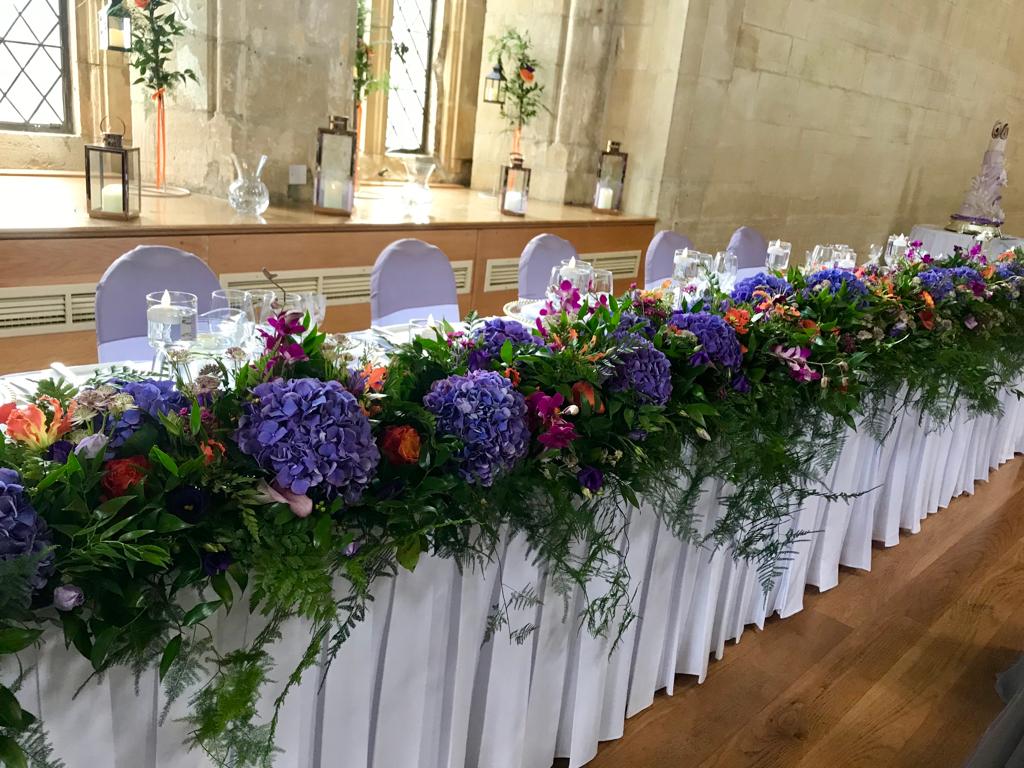 A long table with purple and orange flowers