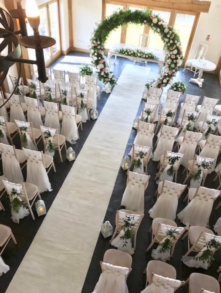 A wedding ceremony is set up with white chairs and a white carpet