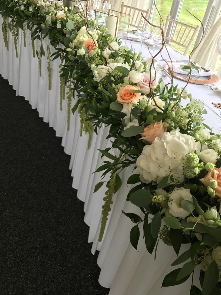 A long white table with flowers and greenery on it