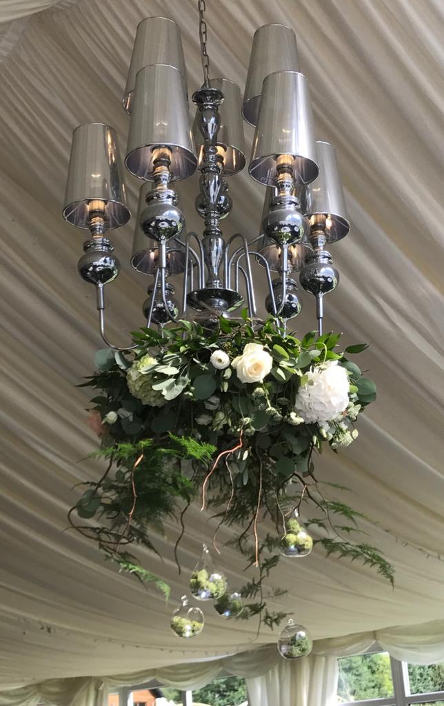 A chandelier with flowers and greenery hanging from the ceiling