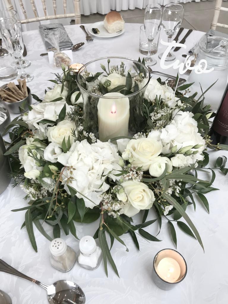 A table with a wreath of white flowers and a candle with the number two written on it
