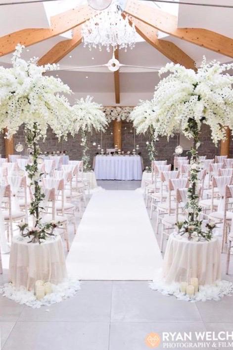 A wedding ceremony with tables and chairs decorated with white flowers
