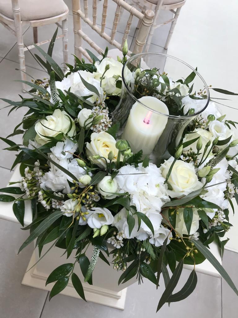 A vase filled with white flowers and a candle in it