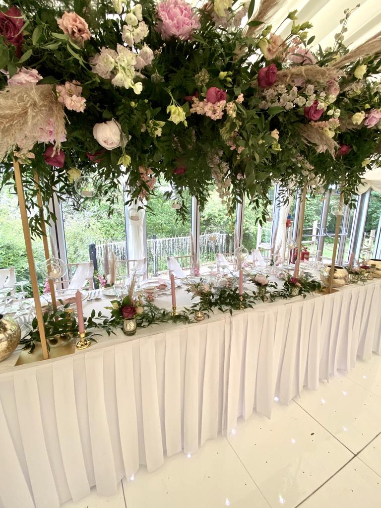 a long table with flowers and candles hanging from the ceiling