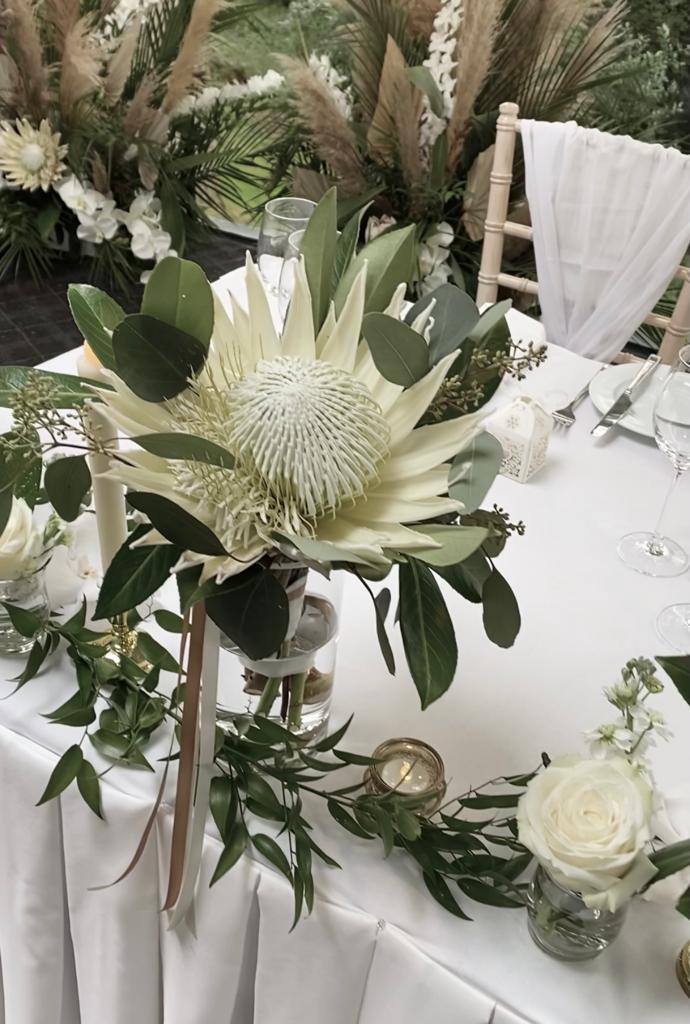 a table is decorated with white flowers and greenery