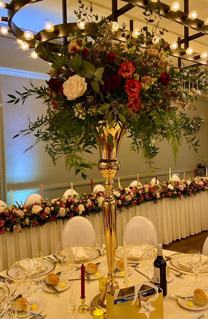 a gold vase filled with flowers sits on a table at a wedding reception