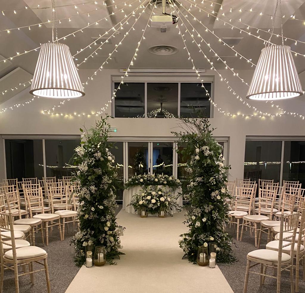 a wedding ceremony is taking place in a room with white chairs