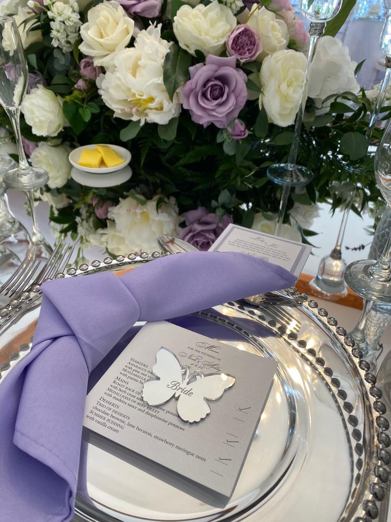 a silver plate with a purple napkin and a menu with the word bride on it