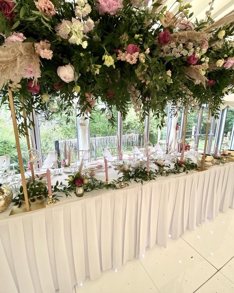 a long table with flowers hanging from the ceiling