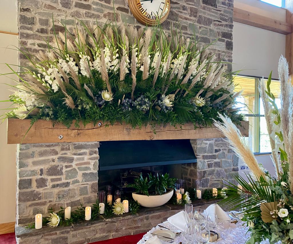 a fireplace with flowers and candles on it