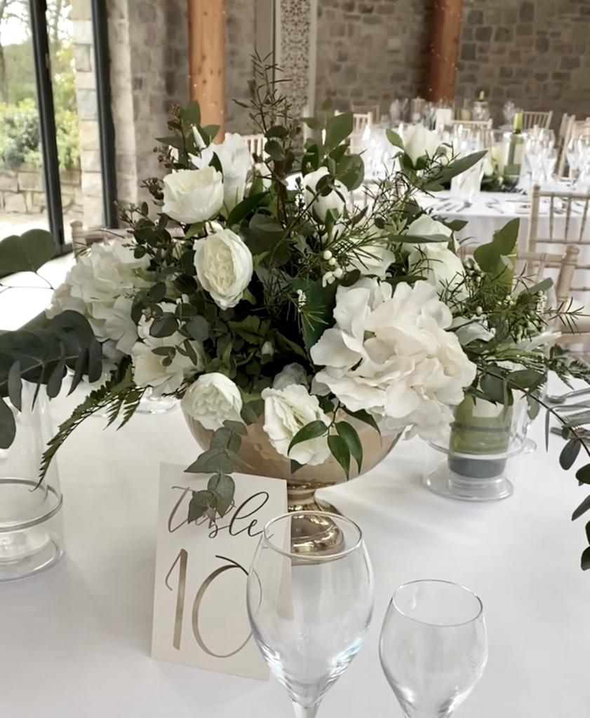 a table with a vase of white flowers and a table number
