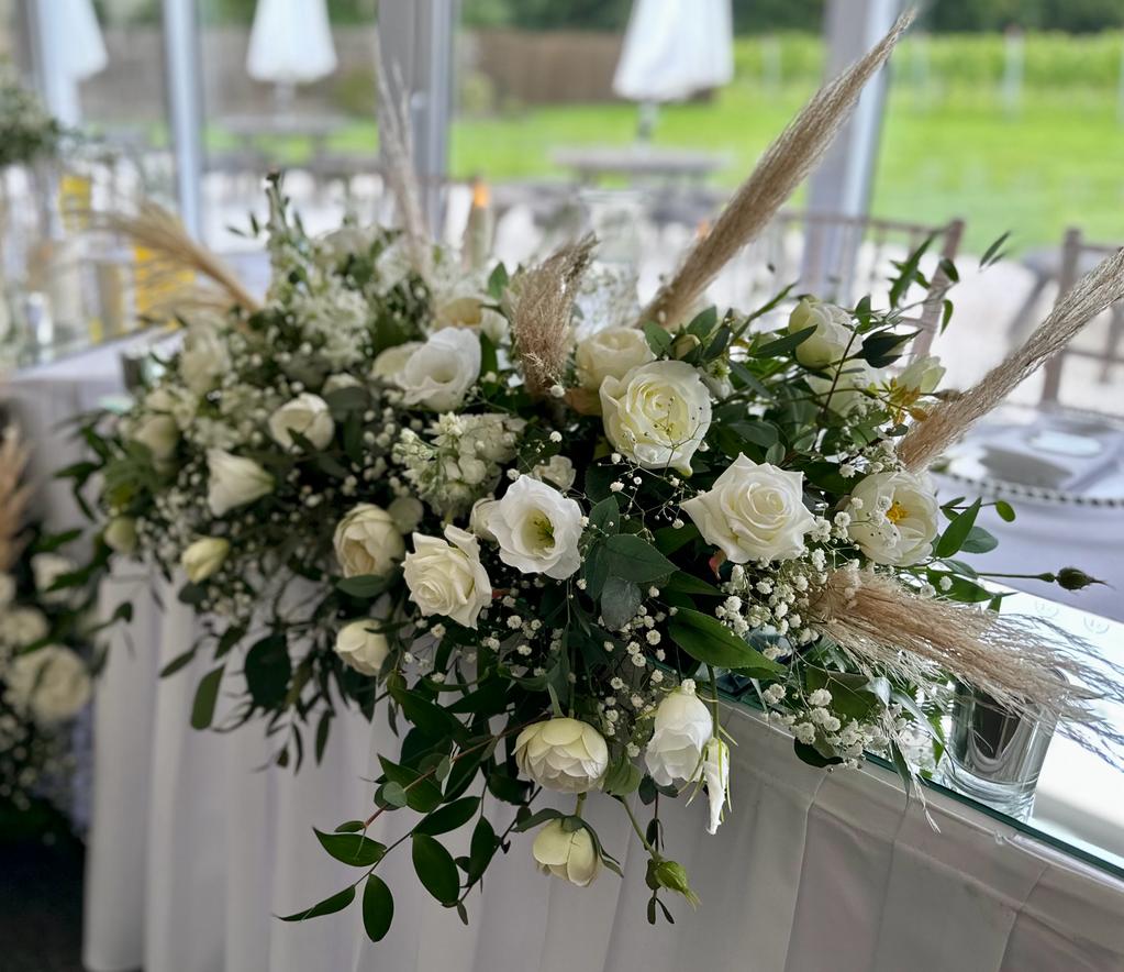 a table with white flowers and greenery on it