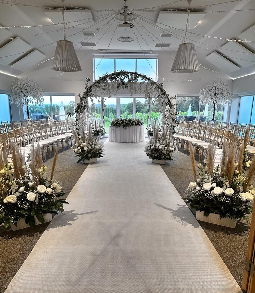 a large room with rows of chairs and a floral arch