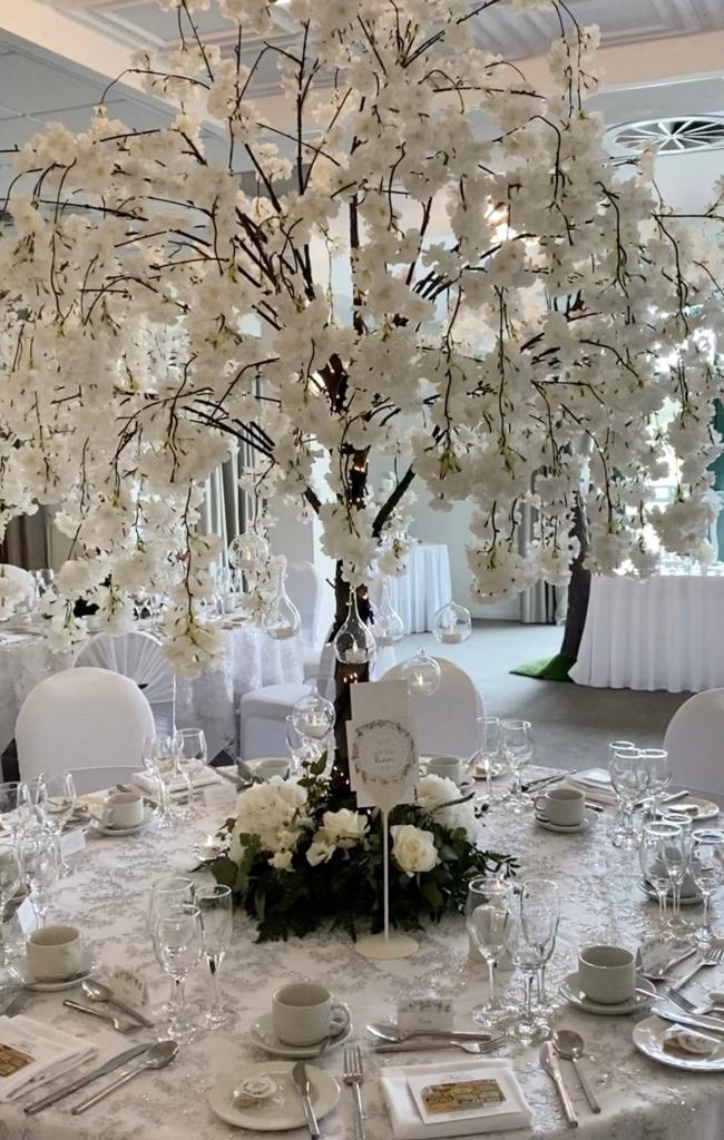 a table setting for a wedding reception with a tree in the center
